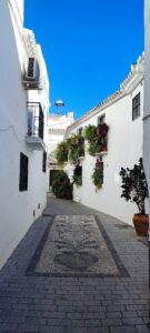 Calle encantadora de Sedella, adornada con encanto rústico y flores coloridas. Una pintoresca estampa que evoca la autenticidad y la serenidad de este encantador pueblo andaluz.